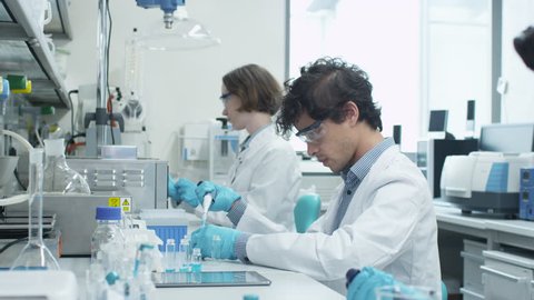 Team of Multiethnic Students in Coats Working in Laboratory of Chemistry Classroom. Shot on RED Cinema Camera in 4K (UHD).