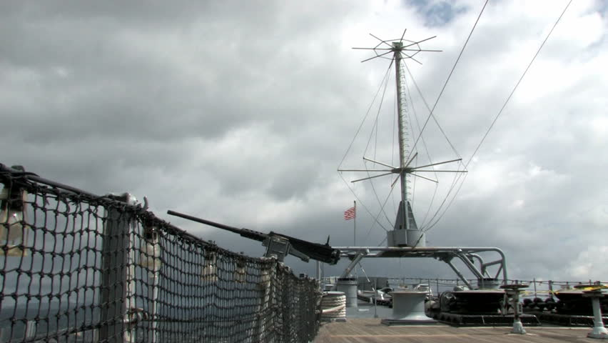 USS Missouri docked at Ford Island in Pearl Harbor, Honolulu, Oahu, Hawaii. 50 caliber machine gun with bullets. Bow of ship with US flag waving in wind.