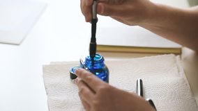 Female writer filling luxury old fountain pen with golden nib with exclusive blue ink from glass bottle - taking extreme care of the vintage pen  - Powered by Shutterstock - Get 15% off with code: PIKWIZARD15