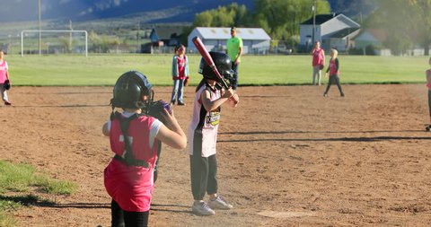 FOUNTAIN GREEN, UTAH - MAY 2016: Young girl rural softball game slow motion. Small rural community. Team spirit teamwork with youth, teenagers and parents. Sports, recreation and healthy exercise.