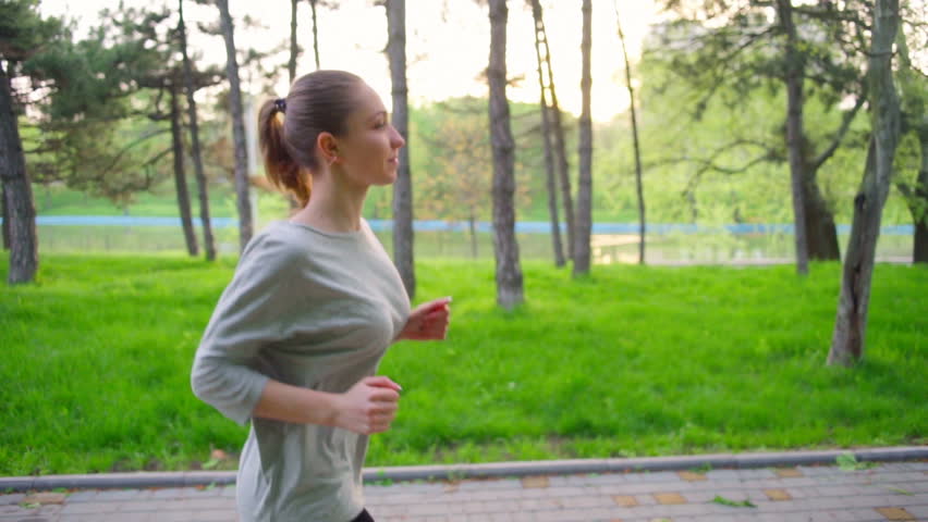 young woman runs in park slow motion