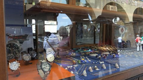 FLORENCE, ITALY - APR. 2016: Arches & tourists reflect window shopping, Ponte Vecchio. Jewelry & watches in shop window. Interesting reflections, Bridge is prime tourist destination for strolling.