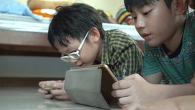 4K, Young asian child playing online games on tablet computer and smart phone .