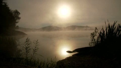 Canoe paddles through early morning fog on lake