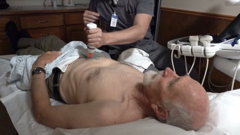 PROVO, UTAH - APRIL 2016: An unidentifiable ultrasound technician preforms a medical abdominal ultrasound procedure on an aging male Medicare patient to check for a descending aortic aneurysm. 
