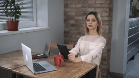 Attractive woman making a video call by tablet in the office during the coffee break.