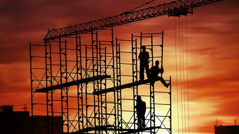Group of workers build house on sunset sky background