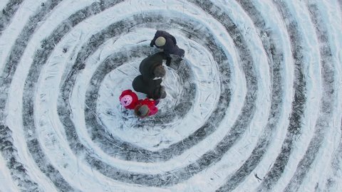 Children and parents start slide by ice spirals near name Ann at winter day. Aerial view