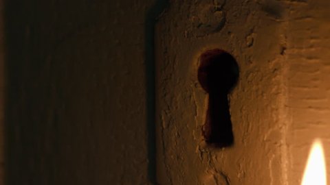 Skeleton key inserted in door by candlelight 
