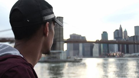 A young, black man looks over the east river at New York City. New York, NY - March, 2016 Video Stok