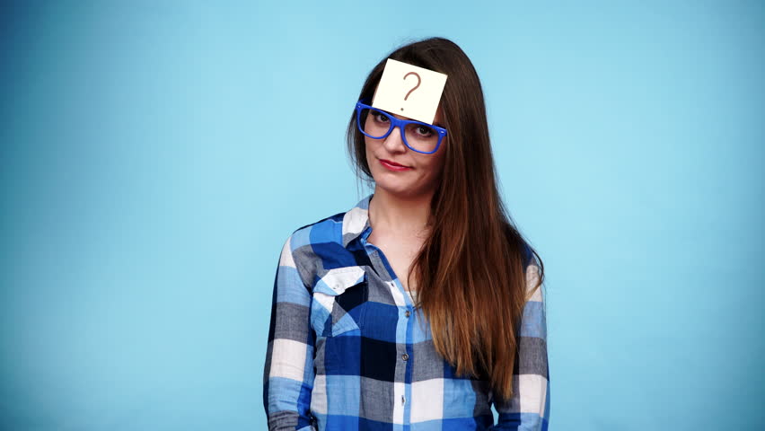 Woman confused thinking seeks a solution, paper card with question mark on her head. Doubtful young female studio shot blue background. 4K ProRes HQ codec Royalty-Free Stock Footage #16653349