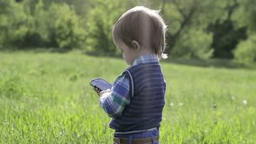 Little boy playing with the phone in nature