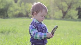 A small child playing with phone in nature