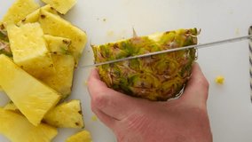 Close video of a man cutting a fresh pineapple.