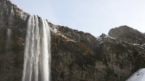 Slowmotion of Seljalandsfoss waterfall close up tilt shot in Iceland in wintertime