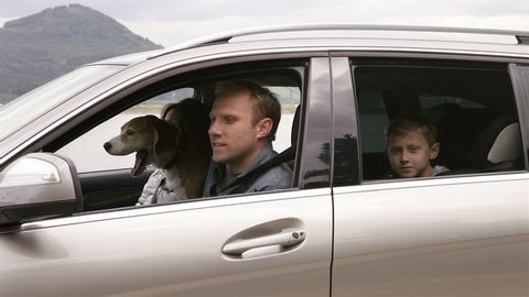 Mother, father, son and beagle dog sitting in the car, fastening belts and move off to the trip