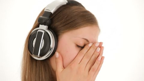 Woman listening to music. A girl in a white shirt and headphones dancing on a white background.