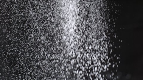 slow motion white flour falling on a black background