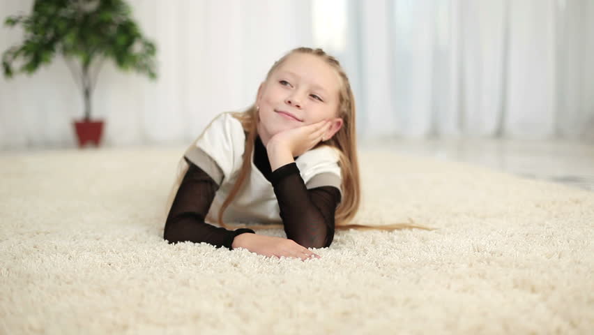 Happy girl lying on the carpet look at camera 