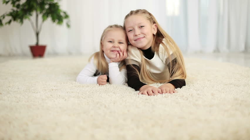 Two sisters lying on the floor and looking at camera 