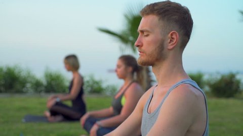 group of people doing breathing practice sitting on grass