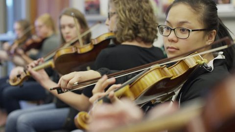 Medium shot of teenage girls playing violins in orchestra practice / American Fork, Utah, United States