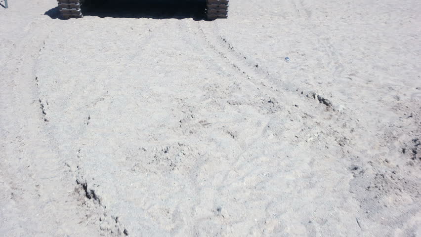 A world war II tank rides on the sand.