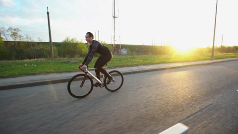 Man riding fixed gear bike on the road at sunset