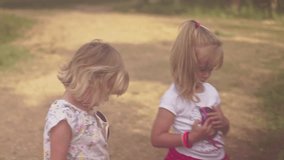 Two little girls take a walk through a forest park on a sunny summer day. Shoot on Digital Cinema Camera in hd.