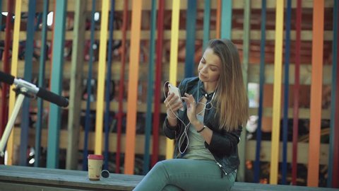Girl listening music from smart phone with scooter