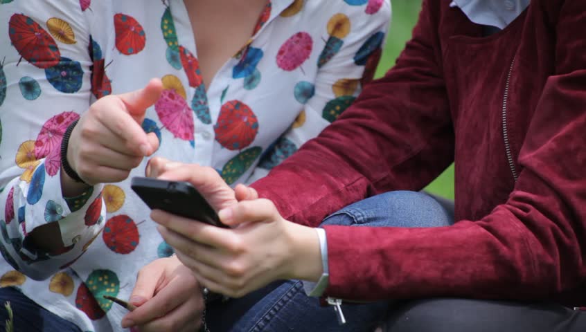 Two Girls Looking at Photos on a Smartphone, laughing,