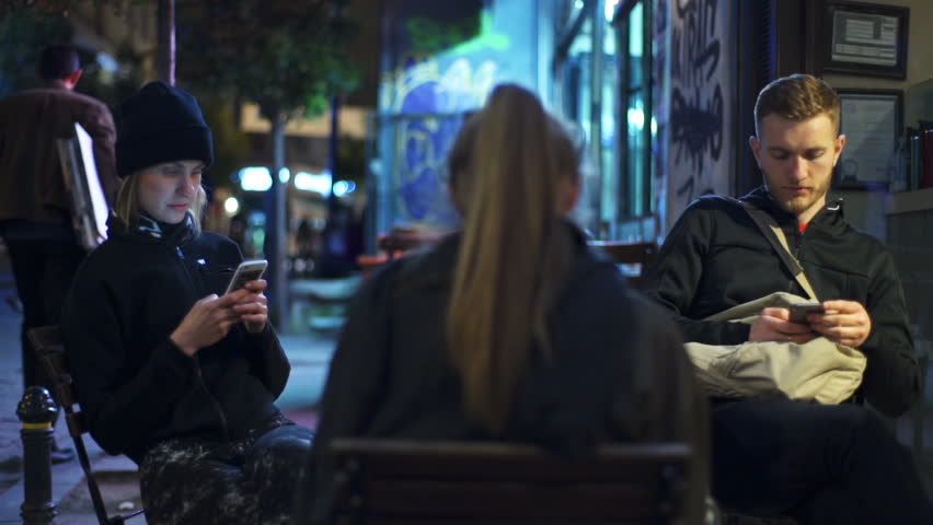 three friends at the cafeteria using their smartphones slow motion