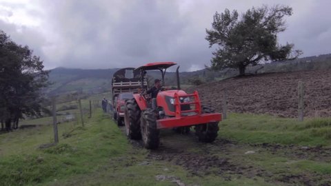 BOYACÃ�, COLOMBIA, CIRCA 2014: Farmer walking behind a red tractor in country field 