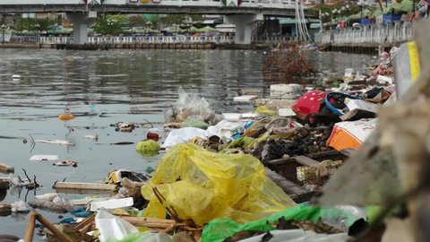 Editorial: Ca Mau, Vietnam, 20th May 2016. Water pollution in Mekong River, plastic bags and other rubbish swimming in the water while a boat is passing.