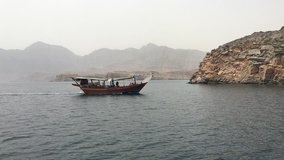 Dhow boat sailing in the waters of Sea of Oman, in Strait of Hormuz, for chasing wild Dolphins, in fjord of beautiful Musandam, a peninsula of Sultanate of Oman.  