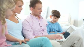 Family of four using laptop to surf the Internet