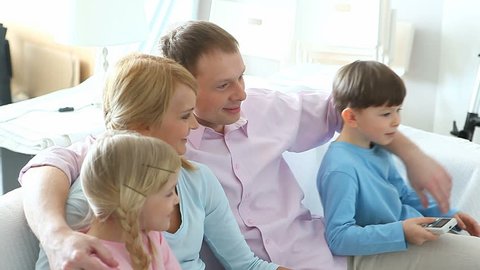 Happy family with kids watching television on the sofa