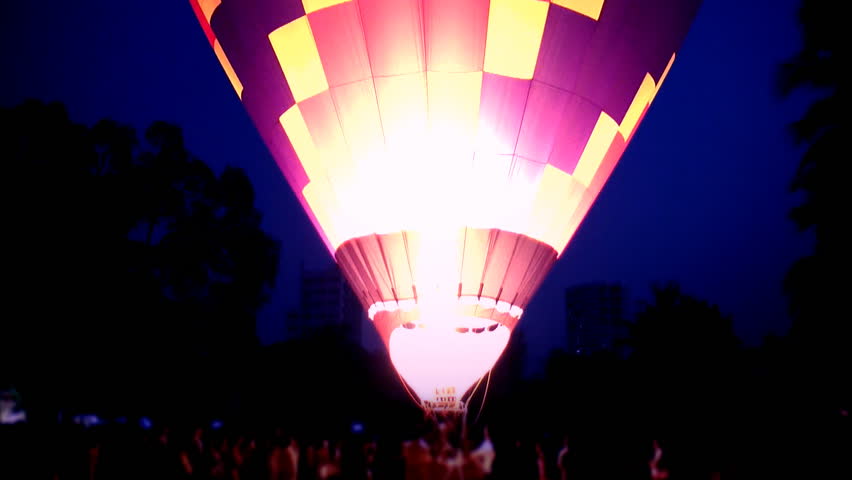hot air balloon fires its burners at dusk