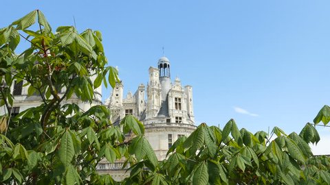 Famous Chateau de Chambord on a summer spring day with warm weather and blue sky seen through trees
