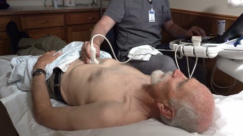 PROVO, UTAH - APRIL 2016: A unidentifiable ultrasound technician preforms a medical abdominal ultrasound procedure on an aging male Medicare patient to check for a descending aortic aneurysm.