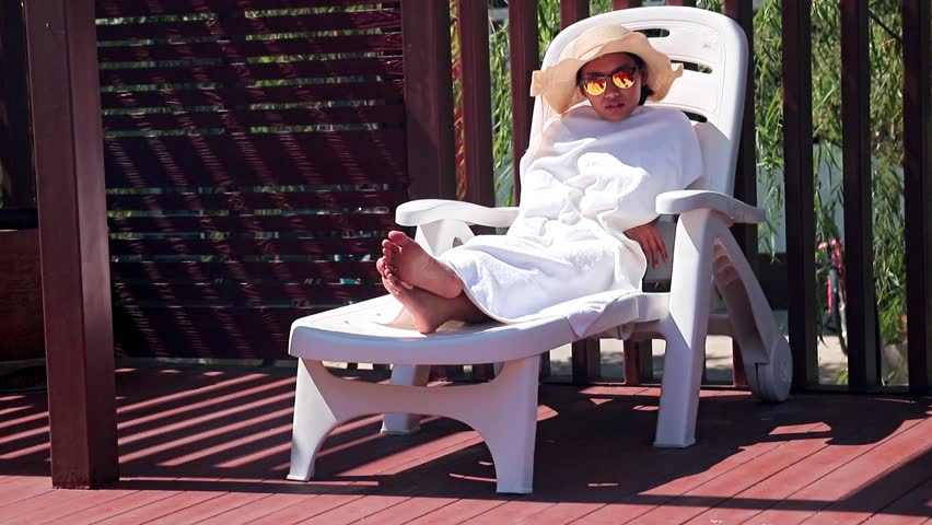 woman on a deck chair wrapped in a towel. Woman lying on a lounger, protect her body from the sun. Protection from the sun.
