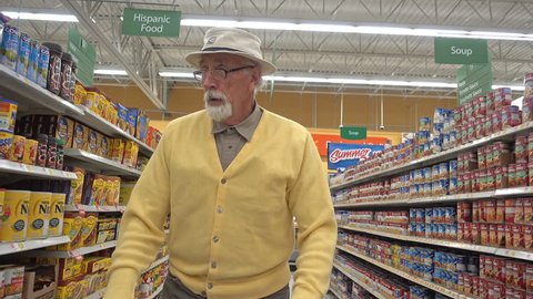 FOUNTAIN GREEN, UTAH - April 2016: Lonely old male senior citizen from the baby boomer generation pushes a shopping cart through the isles of a local grocery store while shopping for groceries.