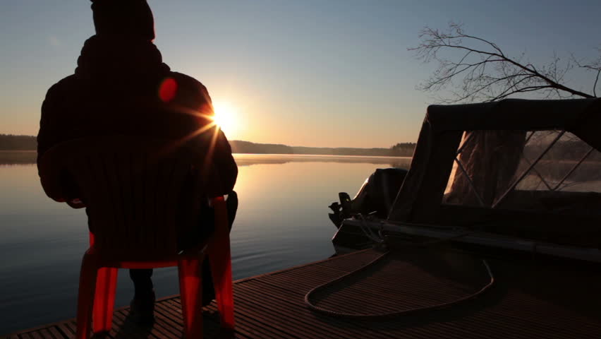 Man admiring a beautiful sunrise in the early morning on the shore of the forest lake