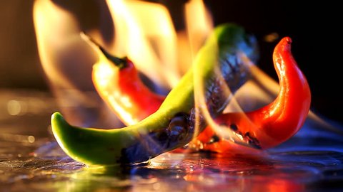 hot pepper in fire arms  /  hot pepper in flames on a black background