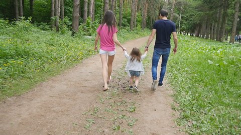 cute baby girl walking in park with parents
