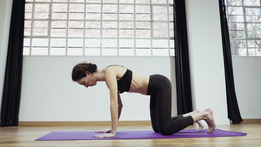 Yoga professional gymnast training exercising in gym, slow motion.A woman practicing yoga,performingstretches routines and exercizes in closed gym in 50fps slow motion.Occasional slider/dolly motion.