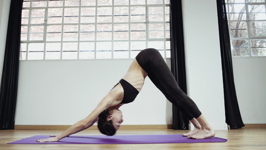 Yoga professional gymnast training exercising in gym, slow motion.A woman practicing yoga,performingstretches routines and exercizes in closed gym in 50fps slow motion.Occasional slider/dolly motion.