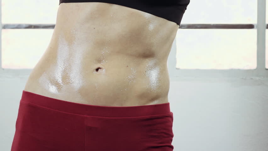 Close up female athlete's/gymnast's toned body,abdomen.A woman practicing dance/aerobic/yoga and performing various stretches routines and exercizes in closed gym in 50fps slow motion, slider/dolly.