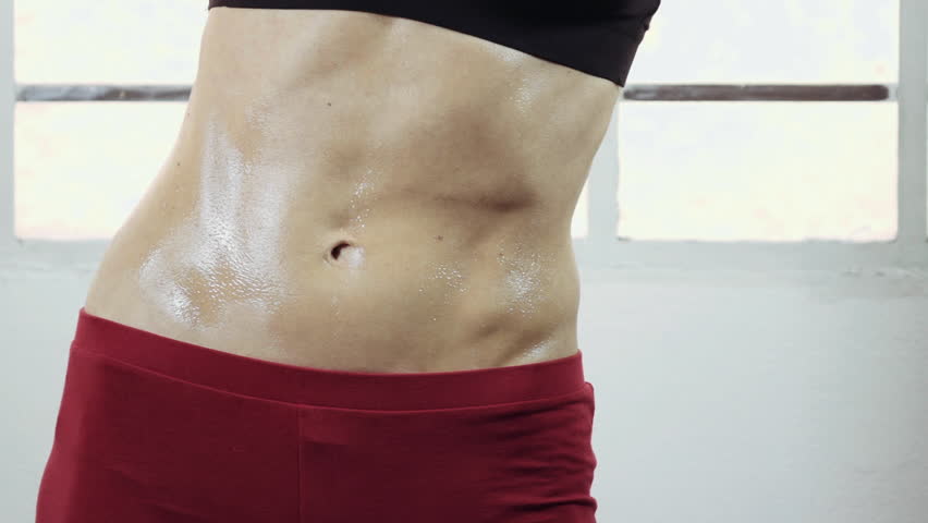 Close up female athlete's/gymnast's toned body,abdomen.A woman practicing dance/aerobic/yoga and performing various stretches routines and exercizes in closed gym in 50fps slow motion, slider/dolly.