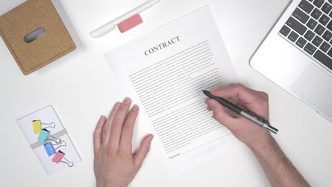 To view of a man hand signing a contract.
